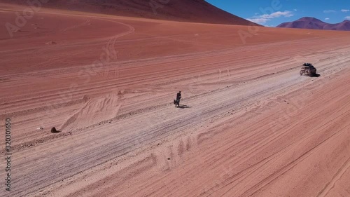 Aerial Parallax Cyclist Riding On Eduardo Avaroa Andean Fauna National Reserve Being Overtaken By 4x4 Car photo