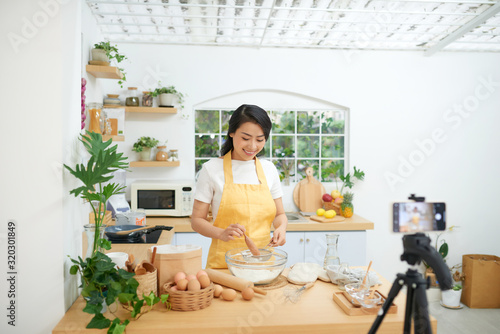 Pretty young asian female food blogger working on a new video and explaining how to cook a dish