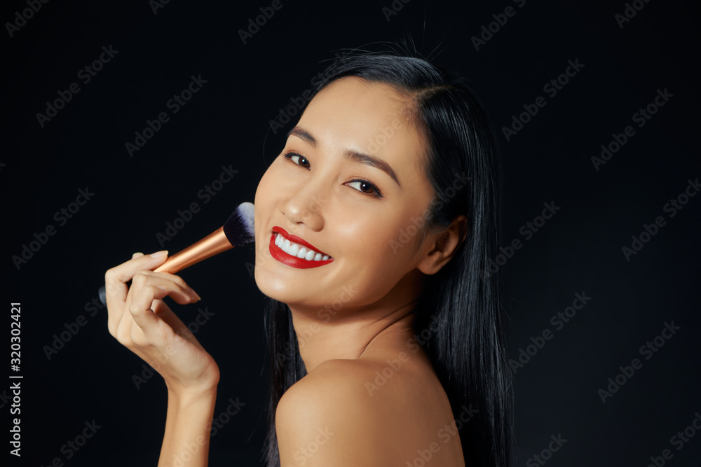 Obraz premium Portrait Of Beautiful Smiling Girl Applying Loose Blush With Cosmetic Brush.