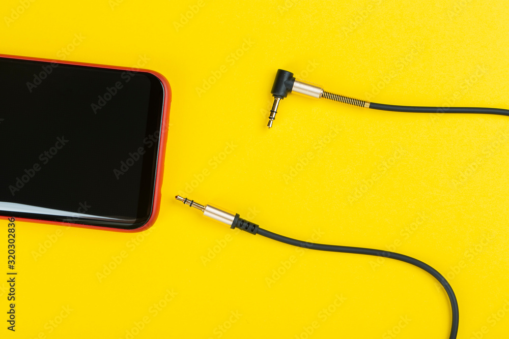Close-up Jack plug and a cable with phone on a yellow background Close-up Jack plug and a cable with phone on a yellow background