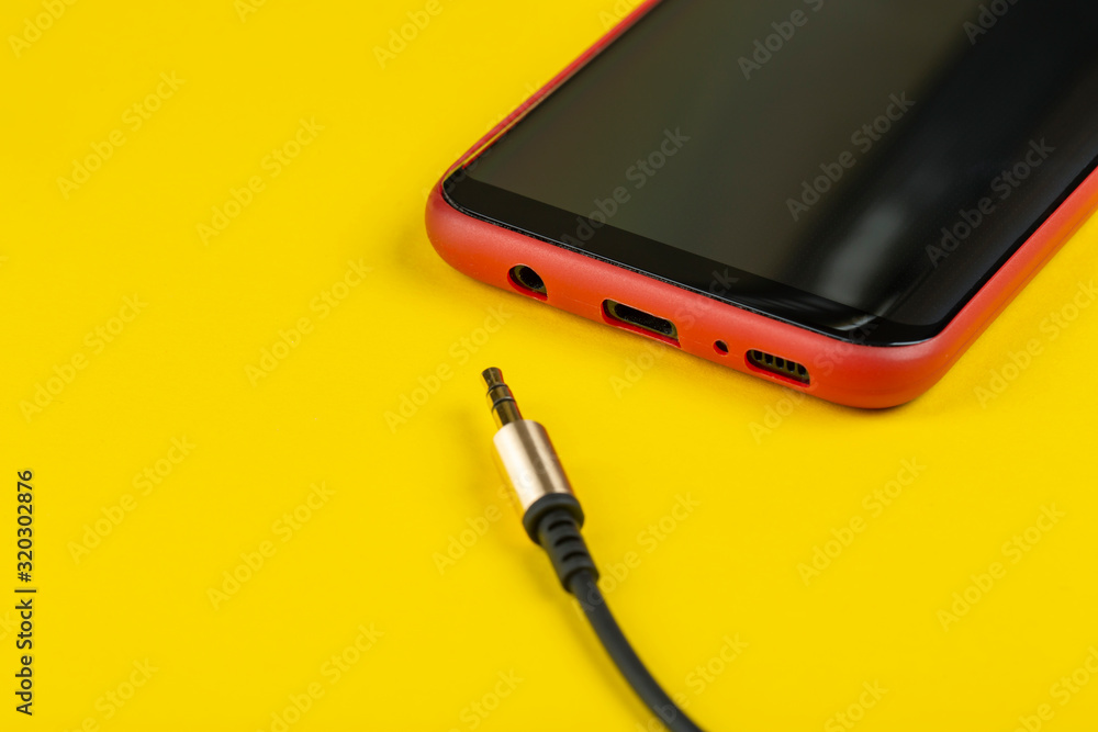 Close-up Jack plug and a cable with phone on a yellow background Close-up Jack plug and a cable with phone on a yellow background