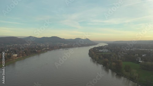 Cinematic drone /aerial shot of the river rhine with a ship and the panorama of the seven mountains / Siebengebirge Königswinter / Bonn at golden hour, 25p photo