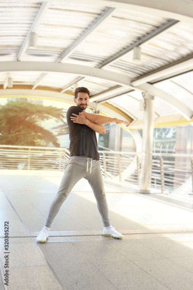 Obraz premium Young runner man stretching body before exercise run outdoor, hansom male jogger athlete training and doing workout in downtown city