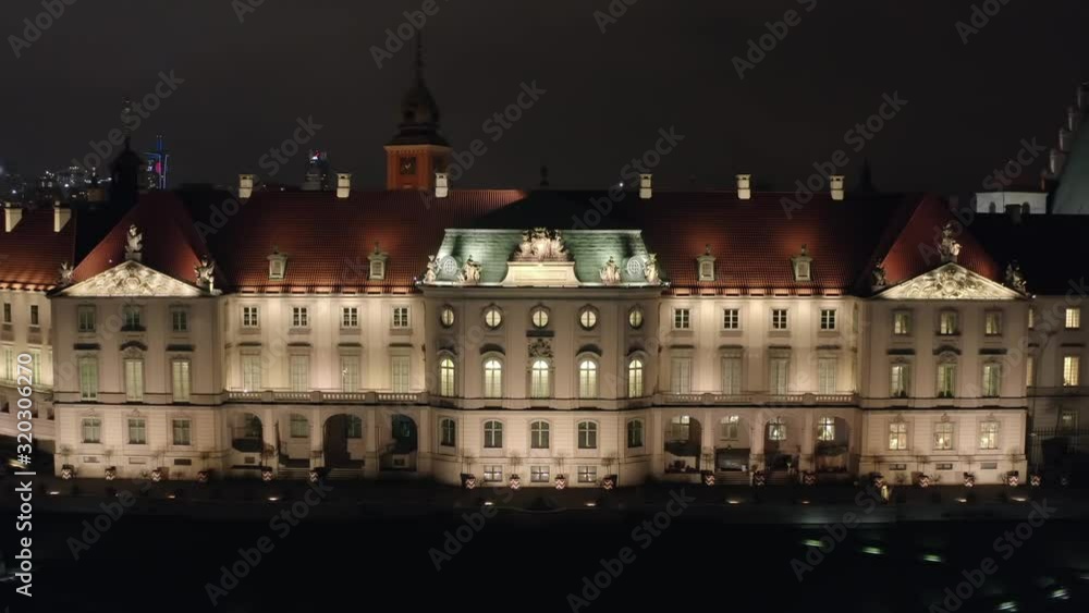 Drone shot on the facade of the royal palace at night. Warsaw, Poland. Aerial view of the night old city with a castle and a palace, the facade of the buildings is illuminated by night lamps. Drone shot on the facade of the royal palace at night. Warsaw, Poland. Aerial view of the night old city with a castle and a palace, the facade of the buildings is illuminated by night lamps.