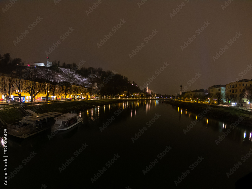 Salzburg in Austria at night view from bridge on river and town, light reflection in water