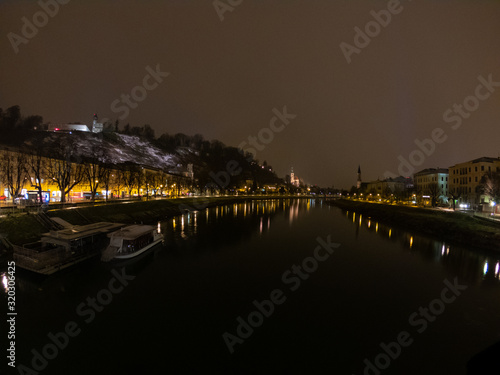 Salzburg in Austria at night view from bridge on river and town, light reflection in water