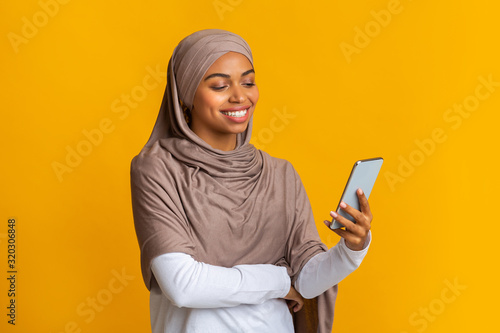 Black muslim girl in headscarf using smartphone, texting or browsing internet © Prostock-studio