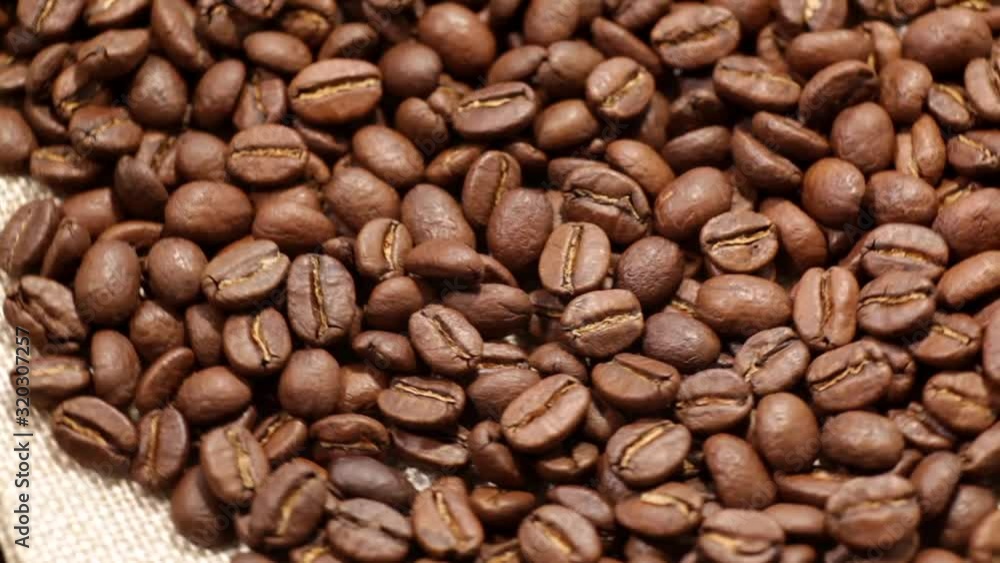 Roasted coffee beans background. Close-up of roasted coffee beans spinning slowly in a circle. Roasted coffee bean background, top view. Roasted coffee beans background. Close-up of roasted coffee beans spinning slowly in a circle. Roasted coffee bean background, top view.