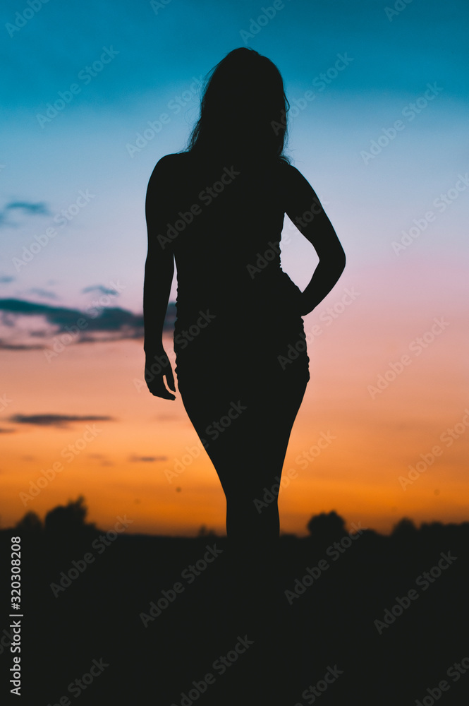 silhouette of attractive woman with a magical sunset in the background