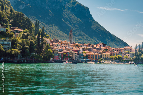 Beautiful panorama of the small town of Varena with its colorful houses and turquoise waters of Lake Como in the foreground, on a sunny summer day, Lombardy, Italy.