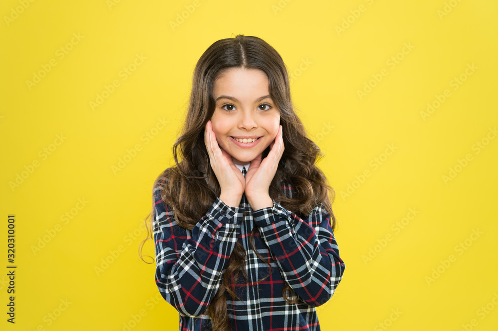 Facial care. take care about her hair. child has long curly hair. after visit to hairdresser. happy schoolgirl in stylish uniform. back to school. small girl checkered dress. kid fashion concept Facial care. take care about her hair. child has long curly hair. after visit to hairdresser. happy schoolgirl in stylish uniform. back to school. small girl checkered dress. kid fashion concept