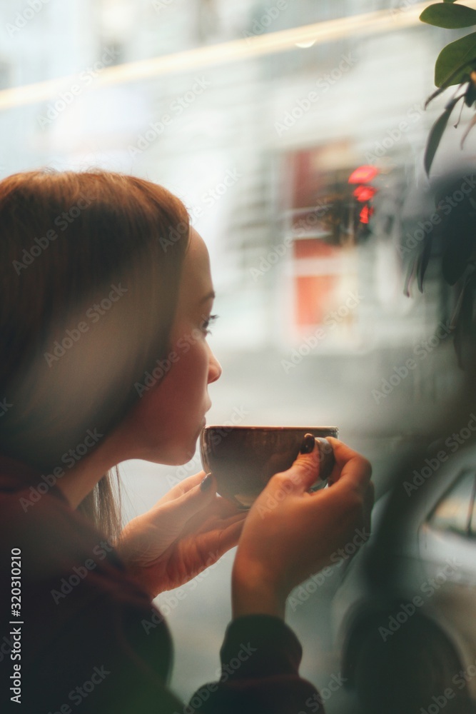 Caucasian young woman enjoying coffee drinking in cafe, close up