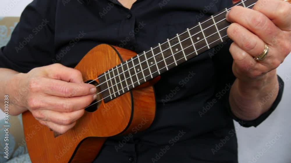 Close up view of woman playing a ukulele, no face, plucking strings, Handheld Close up view of woman playing a ukulele, no face, plucking strings, Handheld