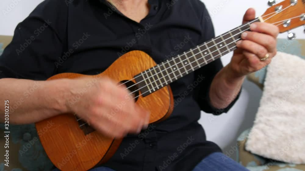 Low down view of woman playing a ukulele, pull away, handheld Low down view of woman playing a ukulele, pull away, handheld