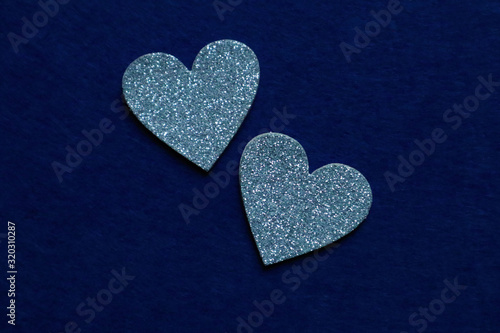 two silver hearts on classic blue background in trendy color of year. Copy space.