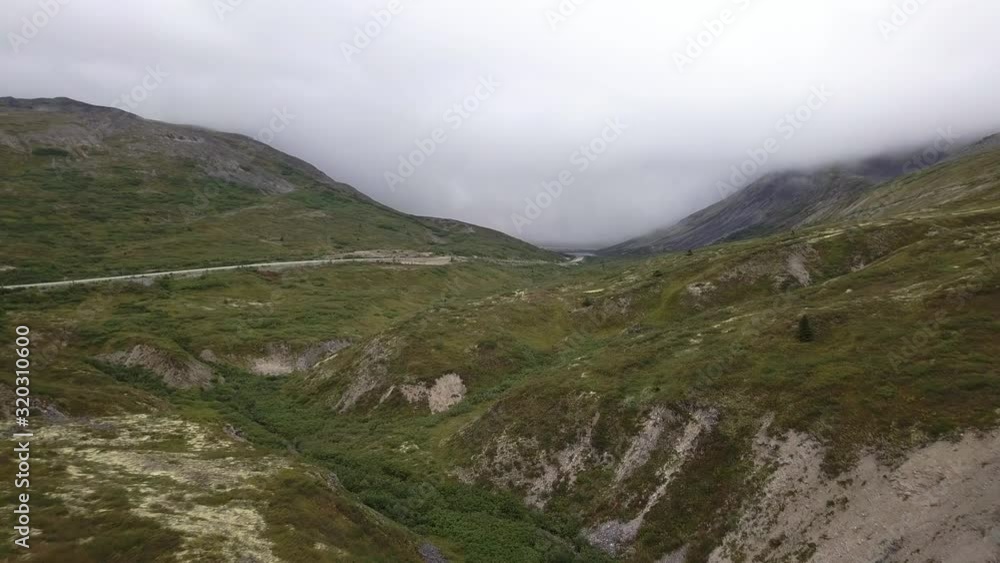 Drone Aerial shot of empty rocky terrain with Haines Highway road surrounded by mountains on a cloudy day. Drone Aerial shot of empty rocky terrain with Haines Highway road surrounded by mountains on a cloudy day.