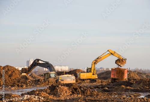 Excavators at a construction site dig the ground for the foundation, laying storm sewer pipes. Road works. Small roughness sharpness, possible granularity