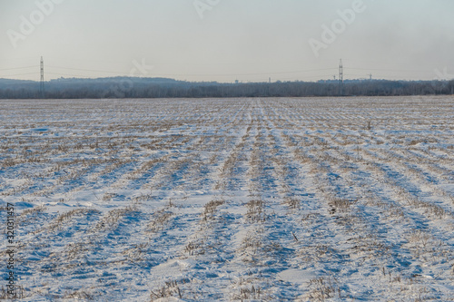 Field with furrows covered with snow in winter
