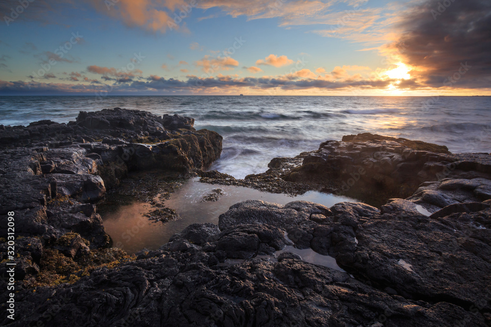 A rocky shore of solidified lava during sunset. A rocky shore of solidified lava during sunset.