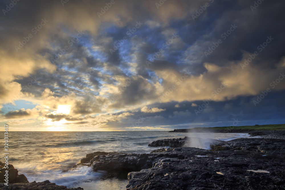 A rocky shore of solidified lava during sunset.