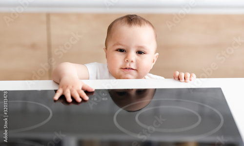 Φωτογραφία Alone curious baby touching hot electric cooktop