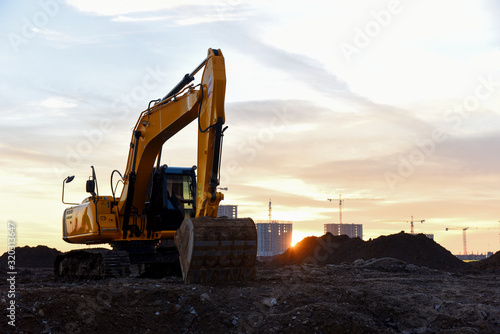 Large tracked excavator at a construction site on the background sunset. 