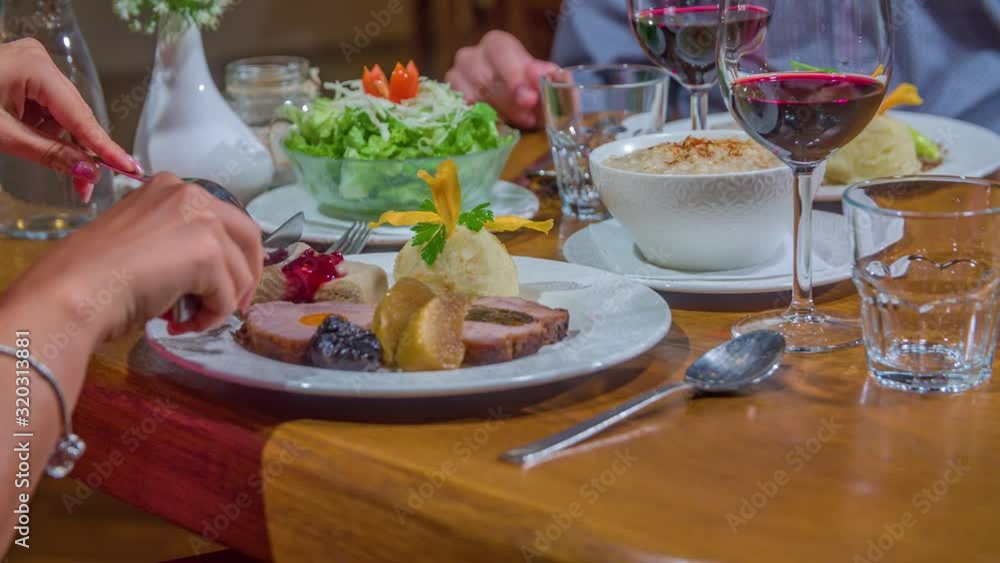 Woman impatiently holding cutlery, wants to start dinner but being stopped to begin to eat Woman impatiently holding cutlery, wants to start dinner but being stopped to begin to eat