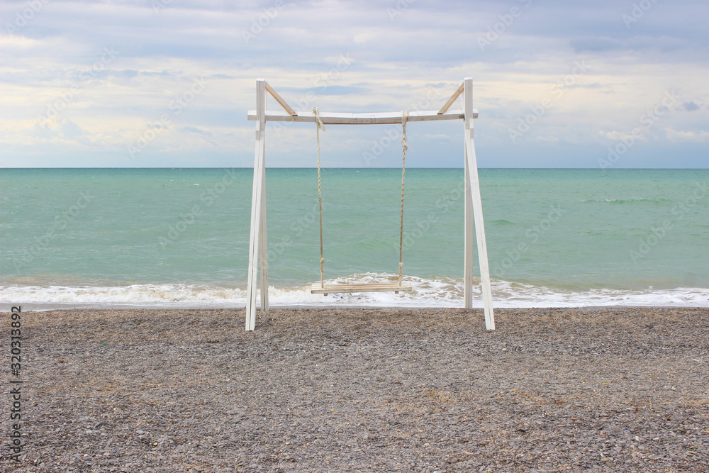 Empty wooden swing on the beach. Empty beach, blue sky. Empty wooden swing on the beach. Empty beach, blue sky.