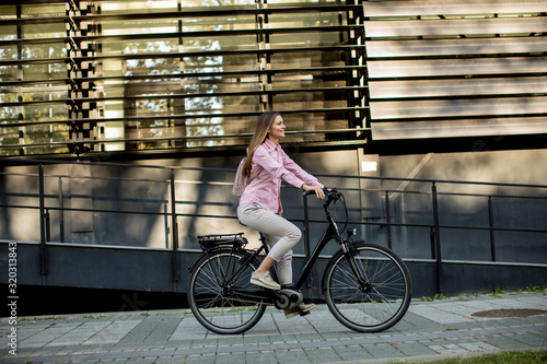 Canvastavla Young woman riding e bike in urban enviroment
