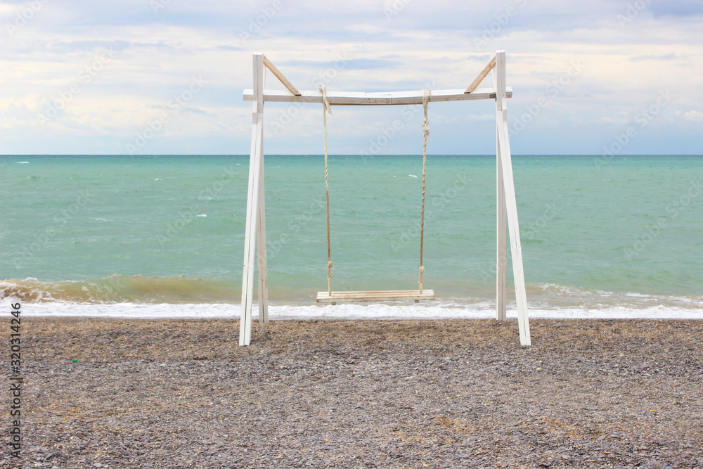 Empty wooden swing on the beach. Empty beach, blue sky. Empty wooden swing on the beach. Empty beach, blue sky.