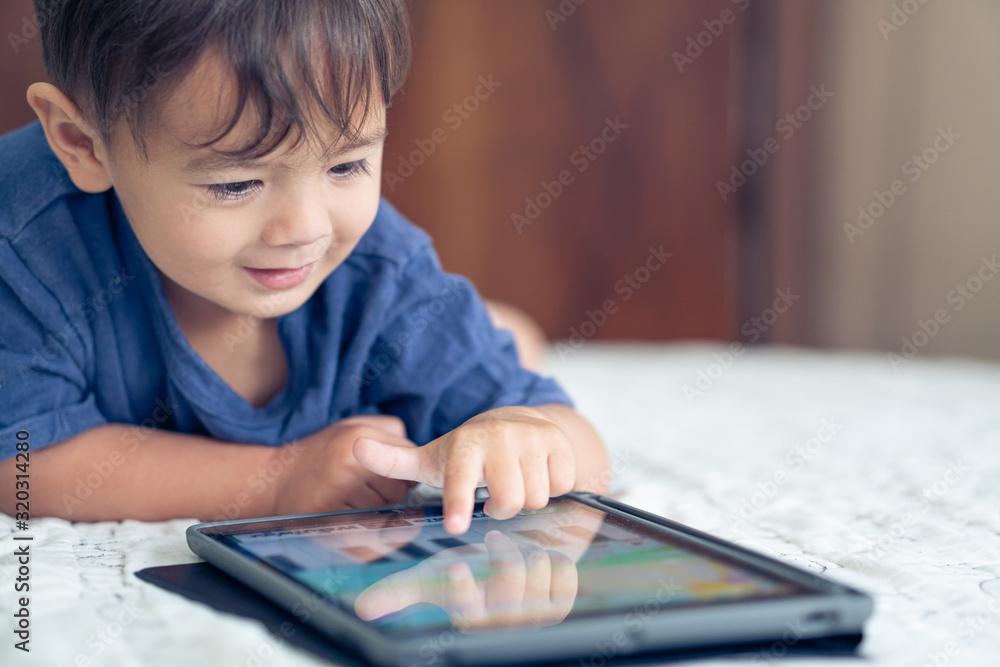 cute young mixed race boy playing with an electronic device cute young mixed race boy playing with an electronic device