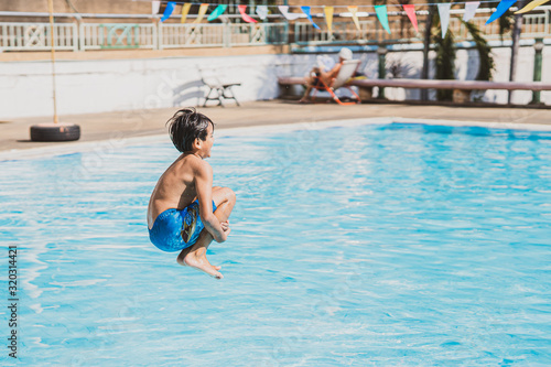 young asina boy jumping into the swimming pool