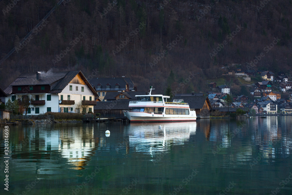 Fototapeta premium Hallstatt, a charming village on the Hallstattersee lake and a famous tourist attraction, with beautiful mountains surrounding it, in Salzkammergut region, Austria, in winter sunny day.