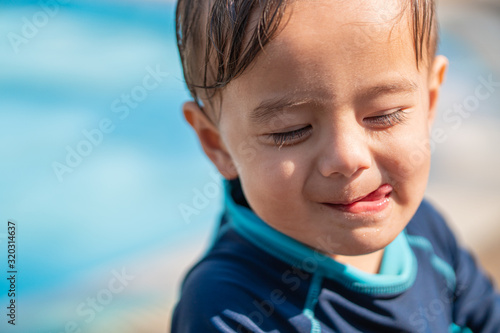 cute young mixed race boy smiling in the sun and licking his lips