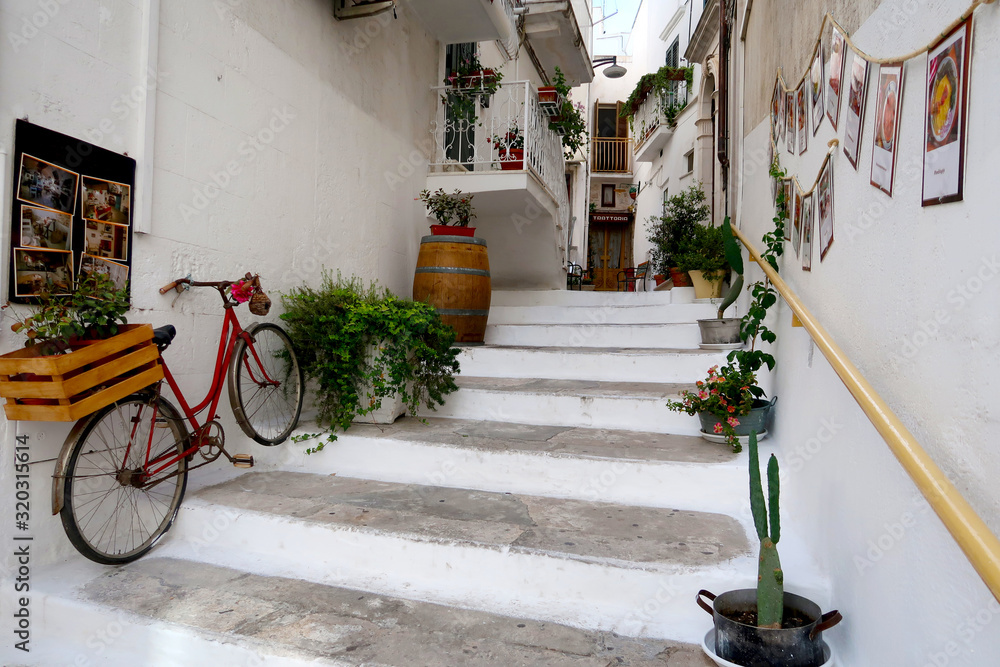 Street of Ostuni town with staircase full of blooming flowers, Apulia region, Italy, Adriatic Sea