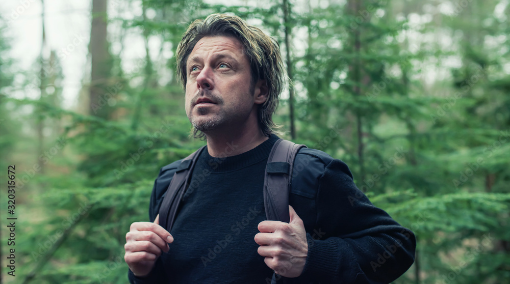 Man in black woolen sweater and backpack hiking in forest. Man in black woolen sweater and backpack hiking in forest.