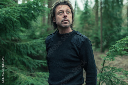 Man in black woolen sweater in woodland.