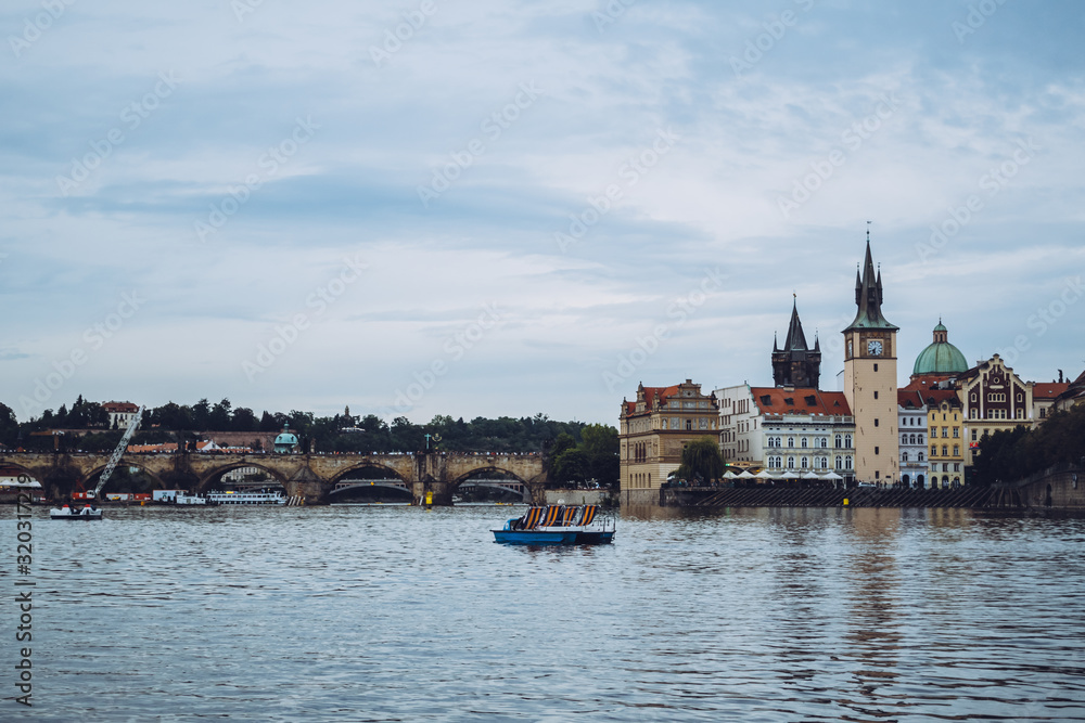 Beautiful architecture of Prague on a calm sunny day over the waters of Vltava river. One of the most popular European travel destinations. Admiring a romantic sunset from a boat.