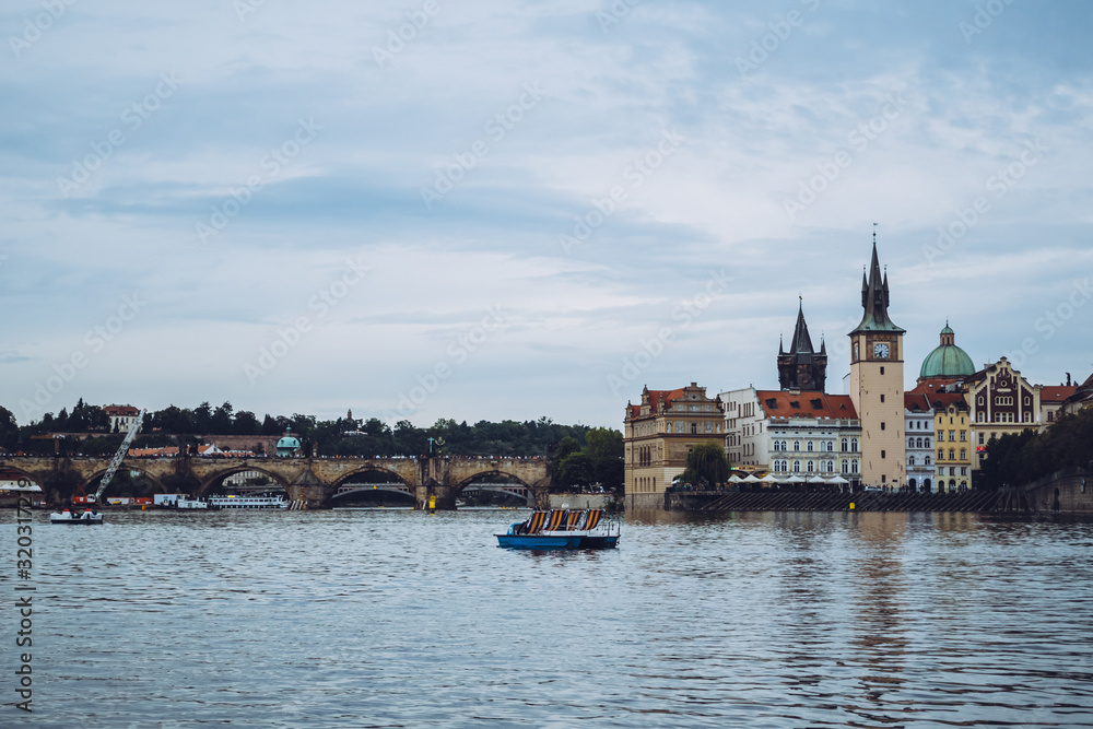 Obraz premium Beautiful architecture of Prague on a calm sunny day over the waters of Vltava river. One of the most popular European travel destinations. Admiring a romantic sunset from a boat.