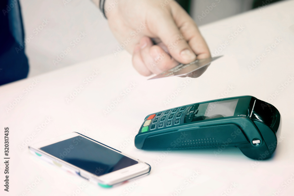 Fototapeta premium Credit card payment. Contactless card payment. A man pays for a purchase in a store with a credit card.