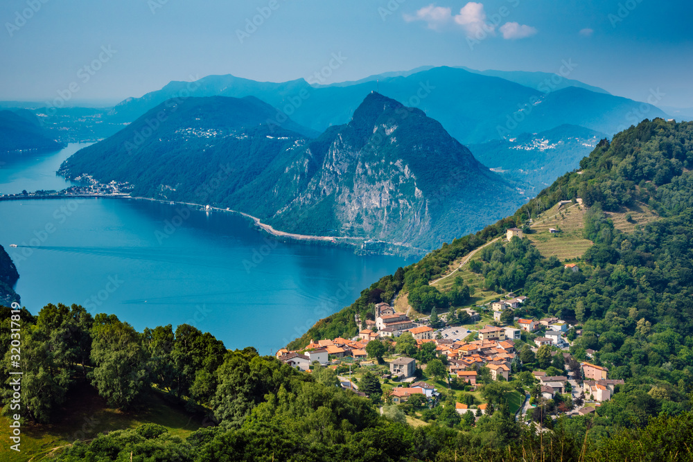 The village of Bre, Lugano Lake , and famous mountains of this area. Beautiful aerial view of a large lake, Swiss village and surrounding high mountains. The photo was taken above the village Bre.