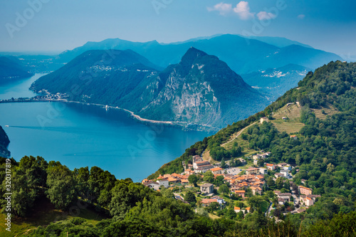 The village of Bre, Lugano Lake , and famous mountains of this area. Beautiful aerial view of a large lake, Swiss village and surrounding high mountains. The photo was taken above the village Bre.