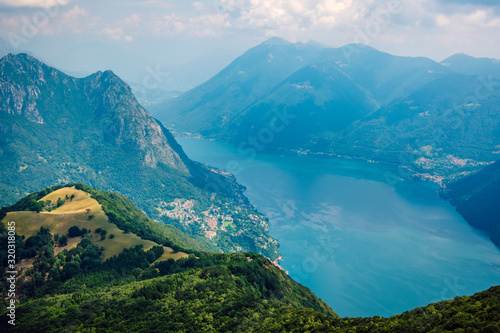 Beautiful summer panoramic view from the Monte Boglia peak to Lake Lugano, Switzerland. A beautiful Swiss lake with blue waters surrounded by high mountains.