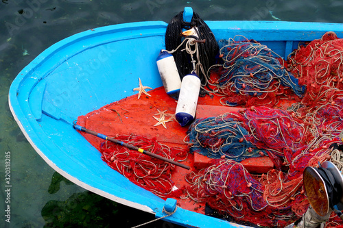 Blue boat full of fishing nets and star fish in the sea harbour of Gallipoli town, Italy, Apulia region, Adriatic Sea