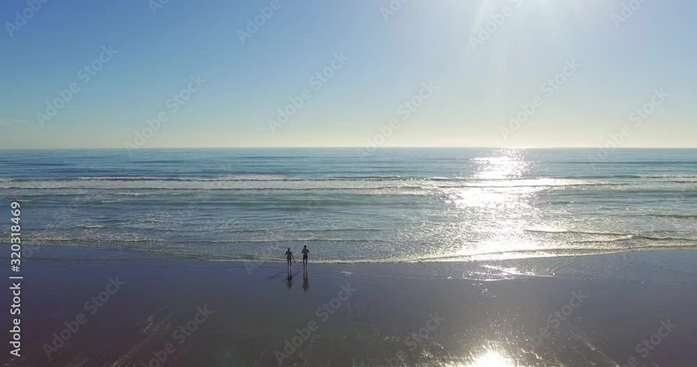 Tourist Enjoy Running Towards The Beautiful Sea in New Zeland With Waves Splashing To The Shore During Sunny Day - Perfect For Summer Vacation - Aerial Shot Tourist Enjoy Running Towards The Beautiful Sea in New Zeland With Waves Splashing To The Shore During Sunny Day - Perfect For Summer Vacation - Aerial Shot