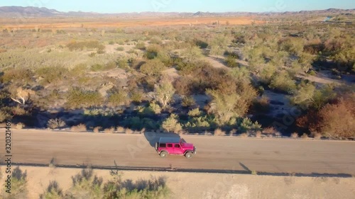 Aerial view of red SUV driving through Mittry Wildlife Refuge and past a spillway- Yuma, Arizona
