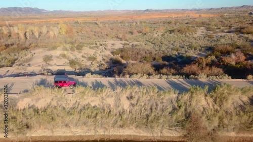 Aerial view of red SUV driving near Mittry Wildlife Refuge and Gila Gravity Irrigation Canal - Yuma, Arizona