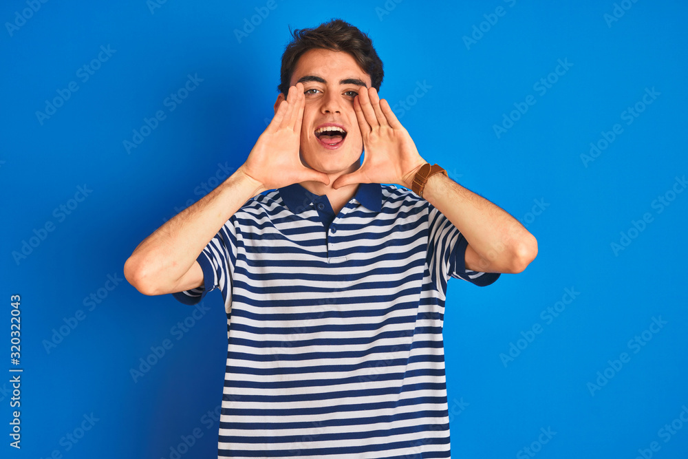 Teenager boy wearing casual t-shirt standing over blue isolated background Smiling cheerful playing peek a boo with hands showing face. Surprised and exited Teenager boy wearing casual t-shirt standing over blue isolated background Smiling cheerful playing peek a boo with hands showing face. Surprised and exited