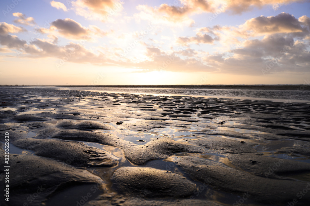 Epischer Himmel am Strand an der Nordsee in den Niederlanden mit Spiegelung des Himmels in nassem Sand