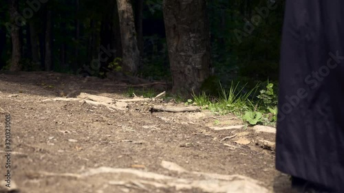 Wallpaper Mural Wandering Missionary Medieval Monk Across Countryside. Man In Black Cloak Coat With Hood Walks On Rural Road In Mountain Forest. Slow Motion Torontodigital.ca